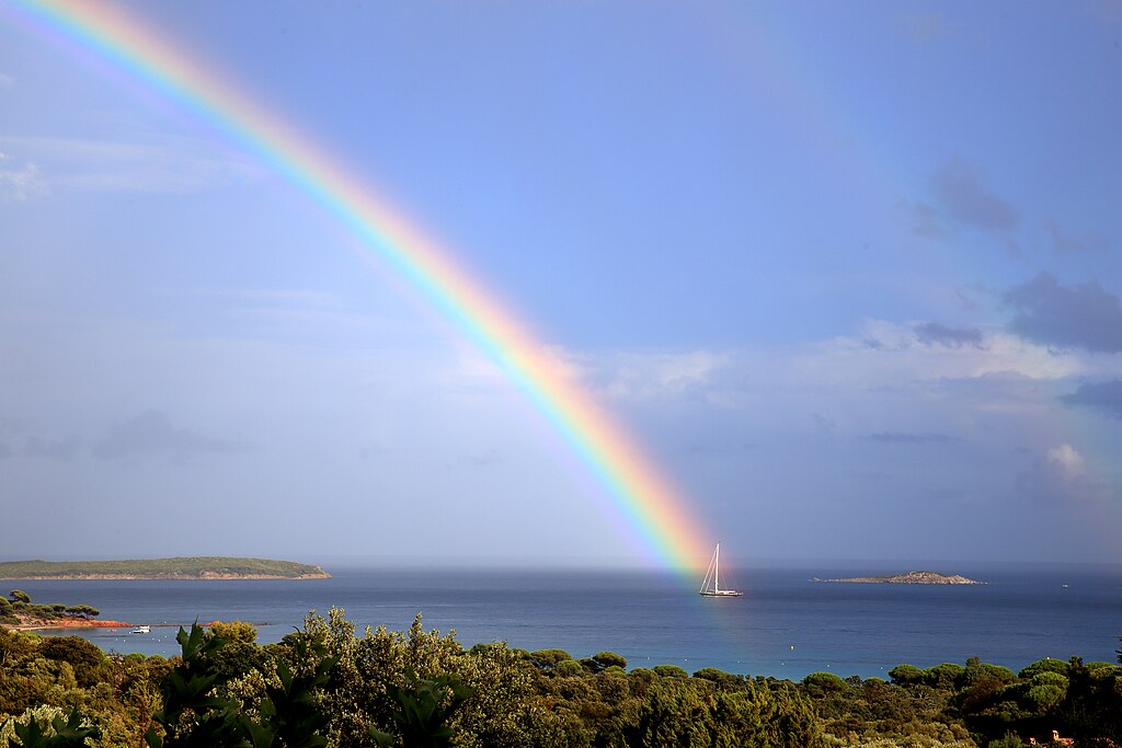 Paysage des îles Cerbicale avec un arc-en ciel, un bateau sur la mer
