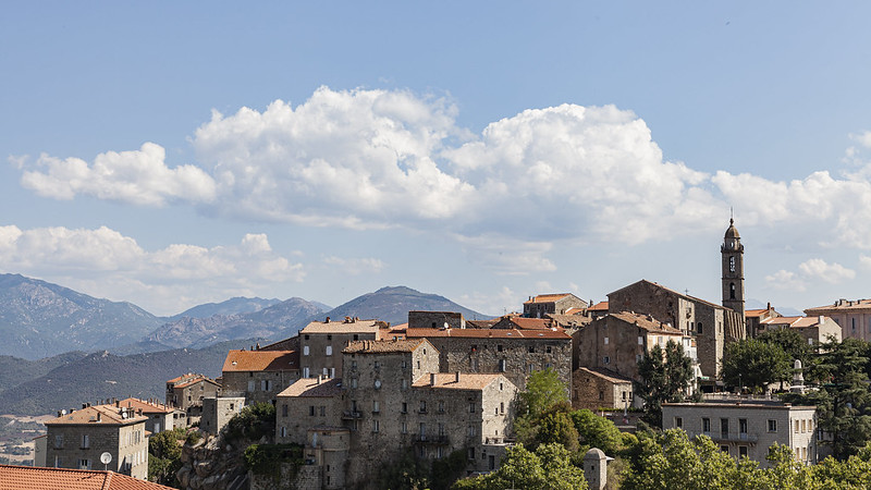 Paysage représentant une vue d’ensemble de la ville de Sartène, ses habitations avec la présence de montagnes en arrière-plan
