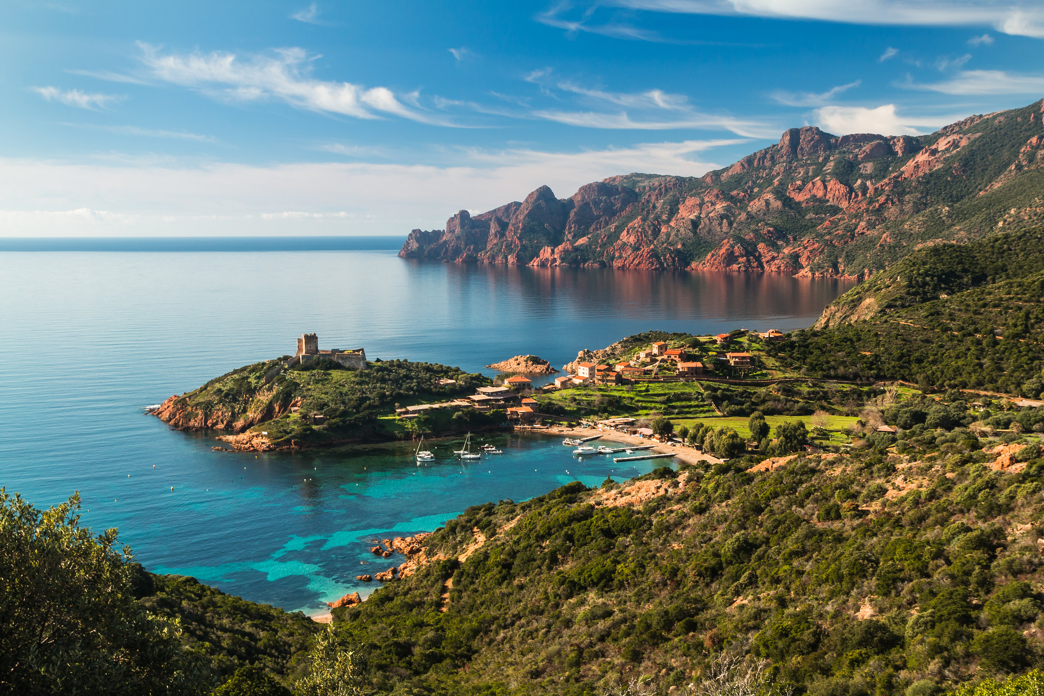 Paysage de Girolata avec mer turquoise, bateaux amarrés, falaises au loin