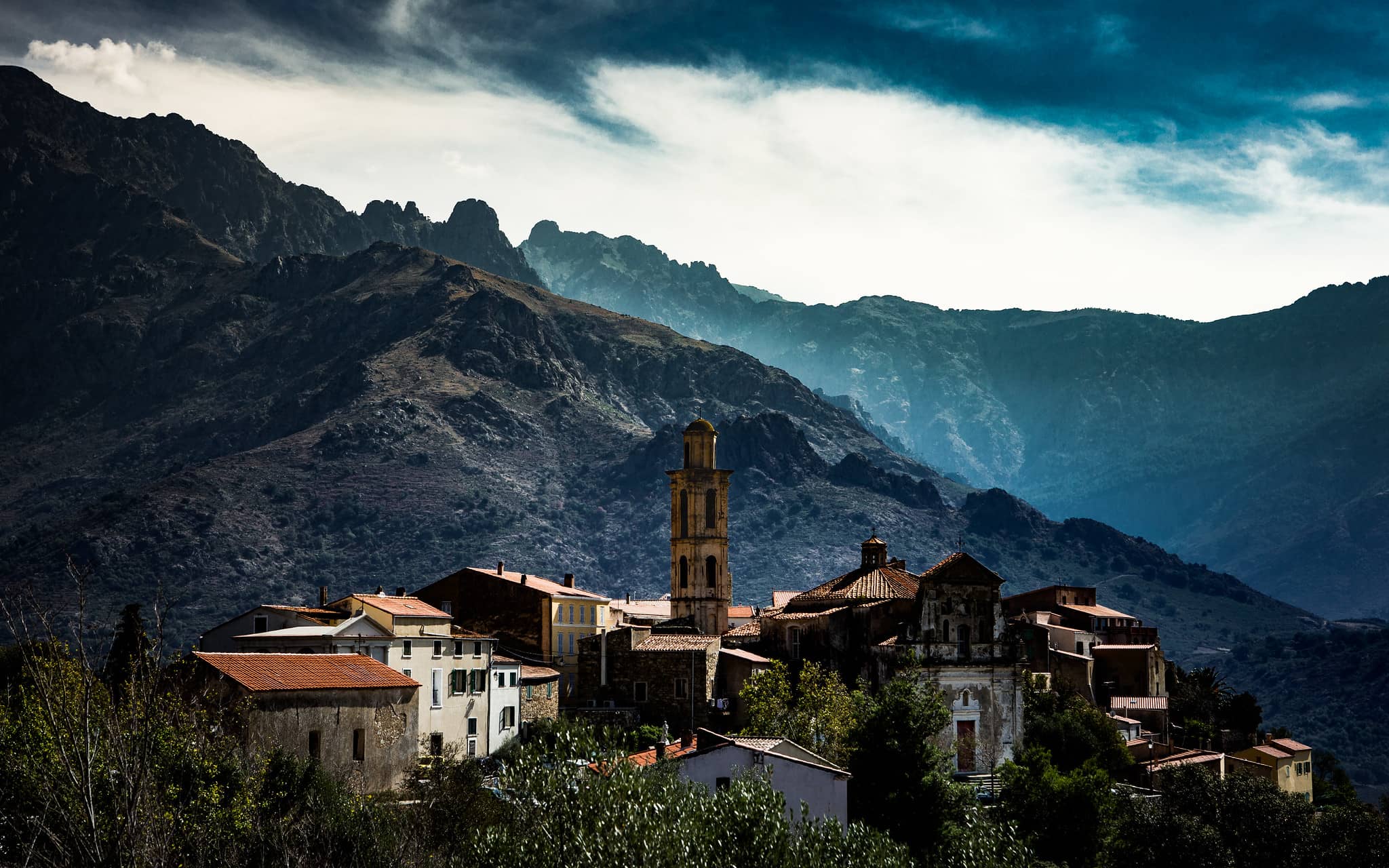 Paysage du village de Montemaggiore avec des montagnes, habitations et du feuillage.