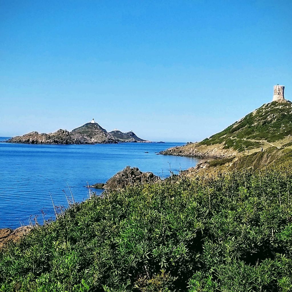 Presqu'île avec une tour génoise séparée par la mer d'îlots avec la présence d'au moins un phare.